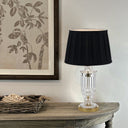 Crystal-look glass table lamp illuminating a reading corner with soft ambient light and a classic tapered fabric lampshade.