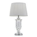 Adria Table Lamp displayed on a bedside table, featuring a crystal-inspired glass base with a white fabric shade for elegant bedroom lighting.