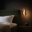 Contemporary hanging ceiling light with a sculptural teardrop glass shade, adjustable suspension, and ambient LED lighting for stylish living spaces.