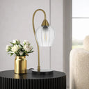 Curved contemporary table lamp creating warm ambient lighting on a bedroom nightstand with a sculptural modern silhouette.
