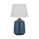 Baci Ceramic Table Lamp displayed on a bedside table, featuring a blue glazed ceramic base with an embossed antique motif and a white fabric shade.