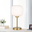 TBobo 1 Light Table Lamp with decorative ribbed glass shade in antique gold finish for modern bedrooms and living roomsable lamp with white glass shade and gold base on a desk with books and flowers.