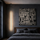 Minimalist architectural floor lamp illuminating a modern living room with a sleek vertical profile and refined black sand finish.
