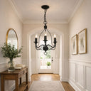 Candice Candelabra Style Pendant with 3 lights in a Foyer with a black chandelier, wooden console table, and framed pictures.