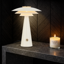 Halvik Beige a Modern table lamp with a candle on a dark surface against a wooden paneled wall.