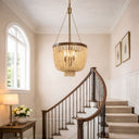 Maddisson Collection Bronze Natural 3 Light Chandelier hanging above a staircase in a well-lit room with a lamp and flowers on a table.