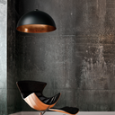 Newport Industrial Large Modern black pendant light fixture hanging above a stylish chair against a textured dark wall.