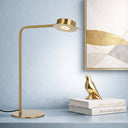 Tarell LED Table Lamp in Antique Gold with gesture-controlled dimming and warm 3000K LED lighting on a decorative bird sculpture on books against a light blue wall with abstract art.