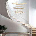 Elegant circular LED chandelier installed above a spiral staircase, producing warm ambient lighting with a striking geometric silhouette.