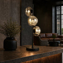 VARLIN Modern table lamp with three glass shades on a dark surface in a dimly lit room.