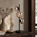 VARLIN A Modern table lamp with glass shades on a wooden surface, next to a vase and books.