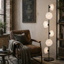 Elegant black floor lamp with smoked textured glass shades bringing soft mood lighting and contemporary character to a stylish lounge.