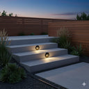 Martec Circa 3W Recessed LED Wall Light Outdoor steps with built-in lights at dusk, surrounded by plants and a wooden fence. Lights and fans online