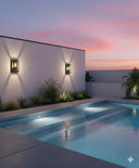 KENT 1 LT MDA Black  Martec Modern pool area with a white wall, plants, and a sunset sky.